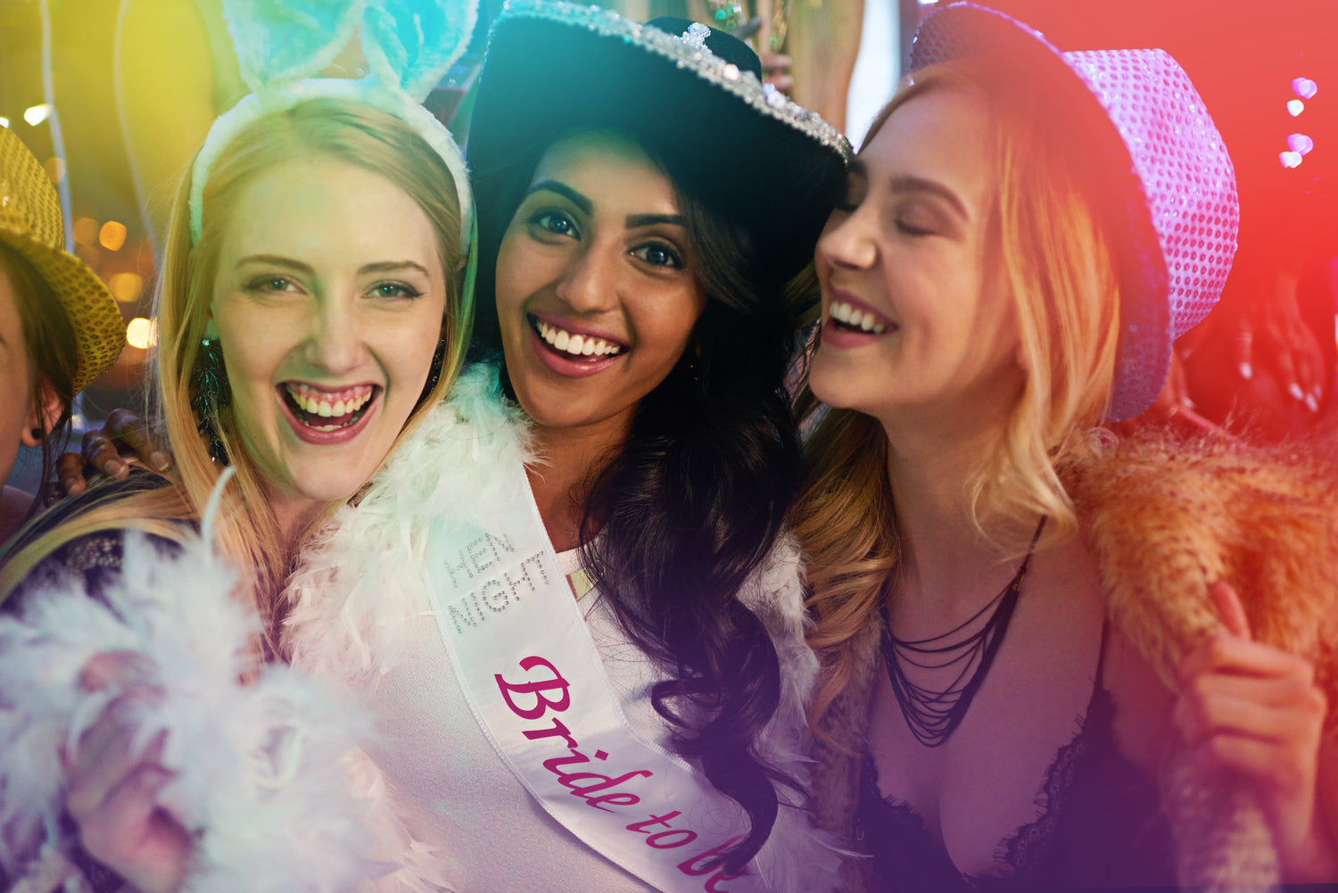 Three women happy on a hen party. Dressed in party hats and hen party sashes