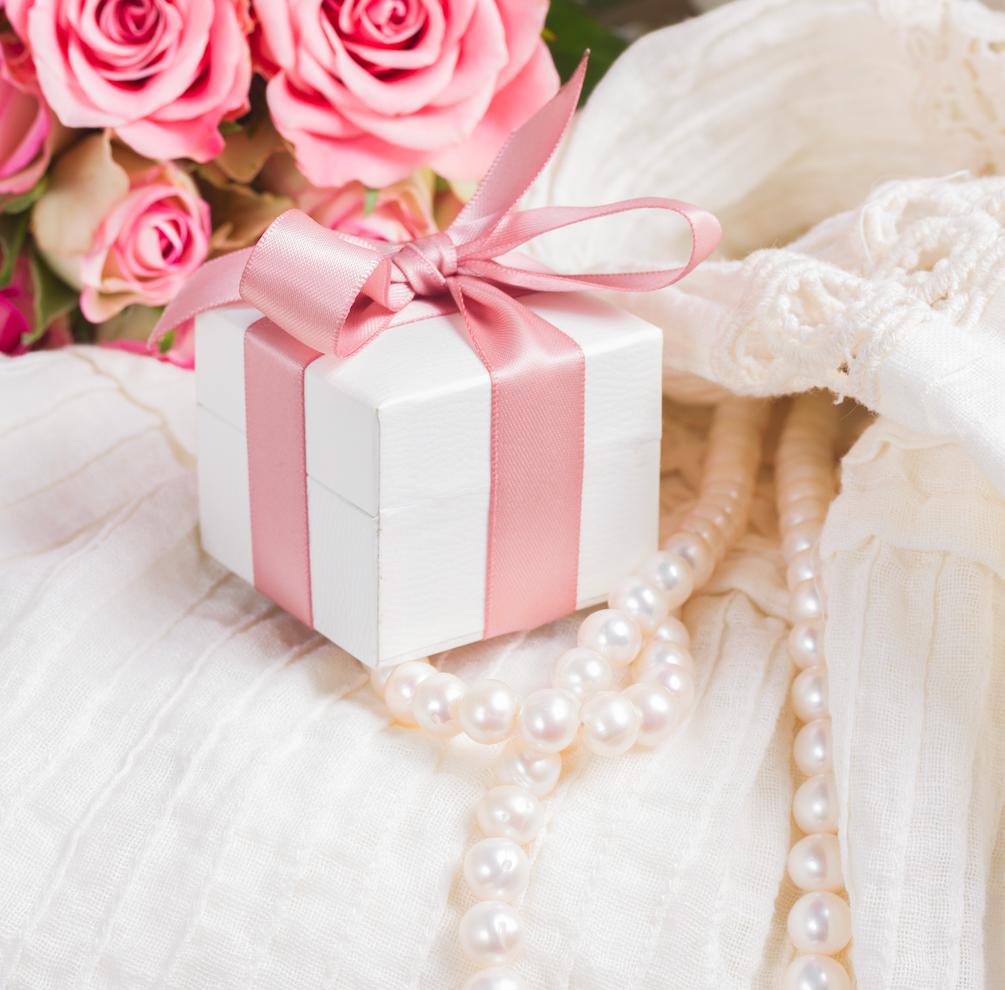 A small white present box wrapped up with pink ribbon with a bow.