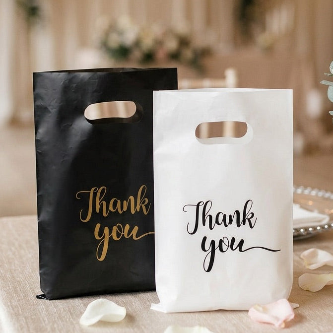 Black and white 'Thank you' bags on a table with floral decorations.