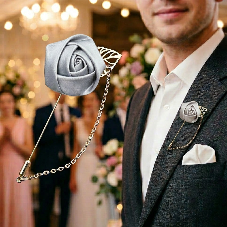 Man wearing a decorative silver rose lapel pin on a blurred wedding background