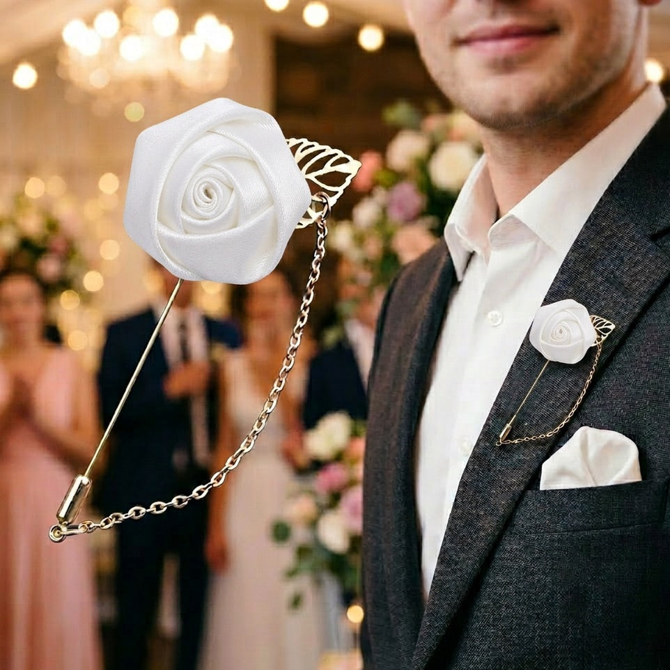 Man in a suit with a white rose lapel pin and matching handkerchief in a festive setting.