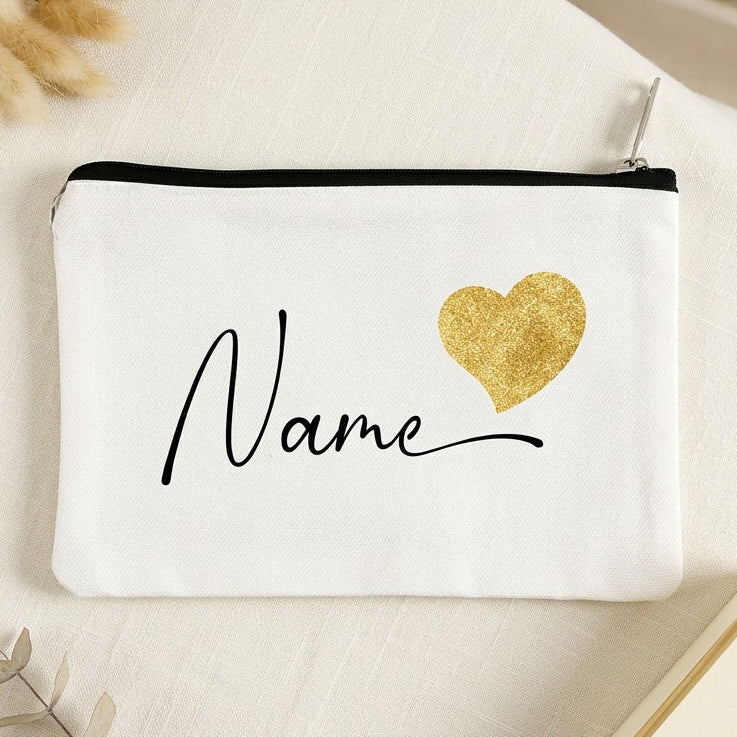 White make up bag with gold heart and 'Name' text on a light surface with decorative elements.