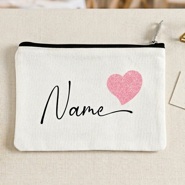 White pouch with pink heart and 'Name' text on a tablecloth, blurred event background