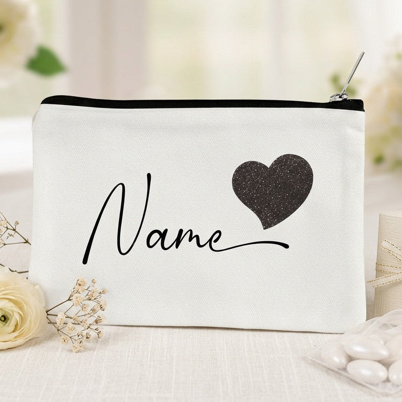 White make up bag with black heart and 'Name' text on a blurred floral background