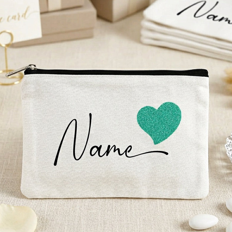 White pouch with 'Name' and green heart design on a decorative surface with flowers and cards.