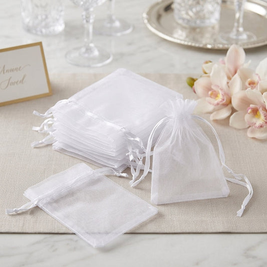 White drawstring bags on a table with flowers and a card in the background