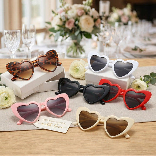 Heart-shaped sunglasses in various colors on a table with floral decorations.