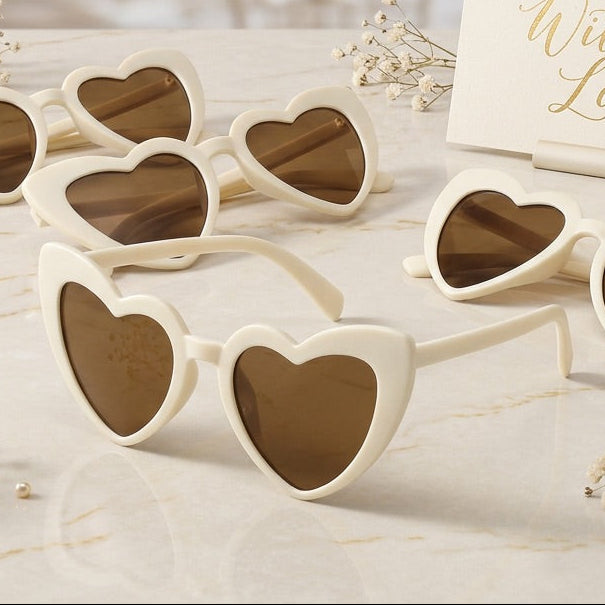 Heart-shaped sunglasses on a table with a 'With Love' card in the background.