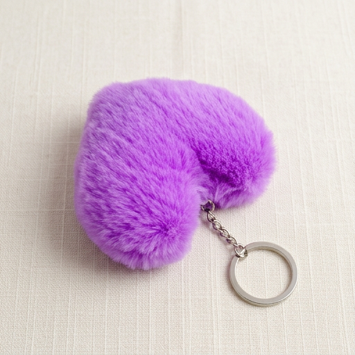 Purple fluffy heart-shaped keychain on a beige fabric background