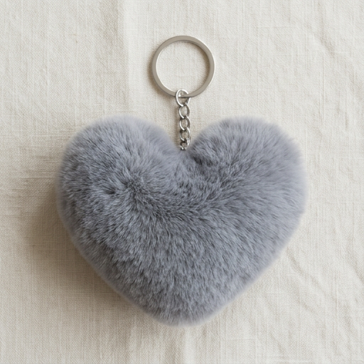 Heart-shaped gray fluffy keychain on a light beige fabric background