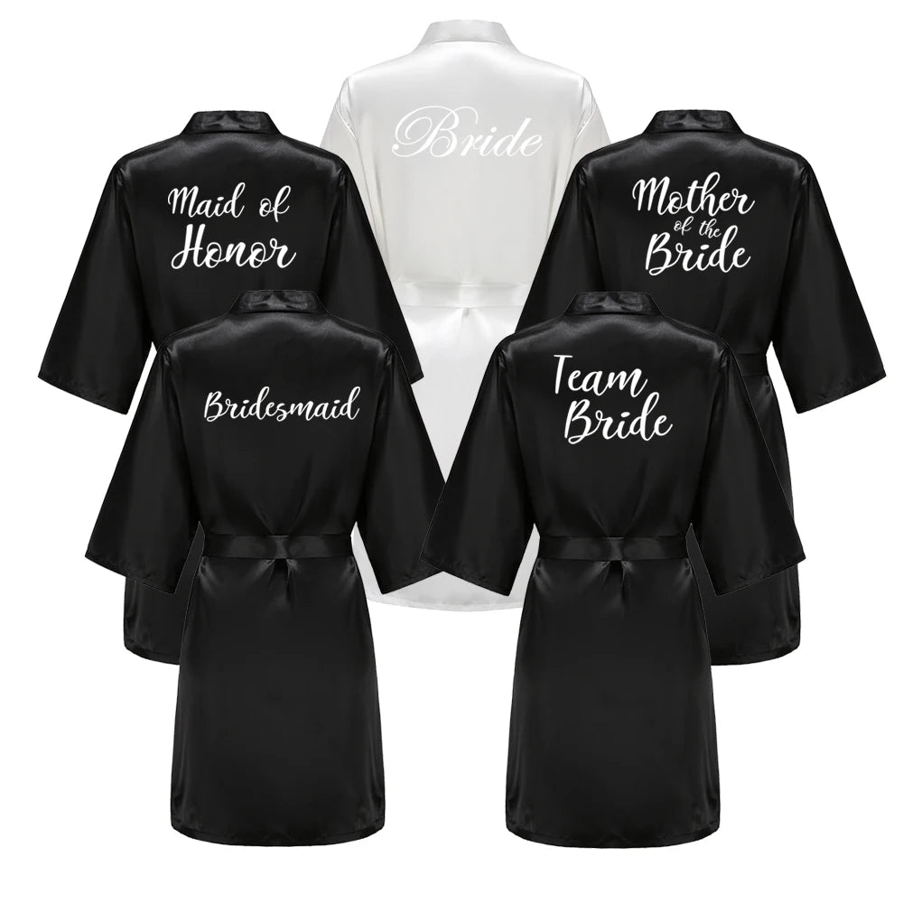 Black bridal party robes with bride, bridesmaid, mother of the bride, team bride and maid of honour text on the backs.