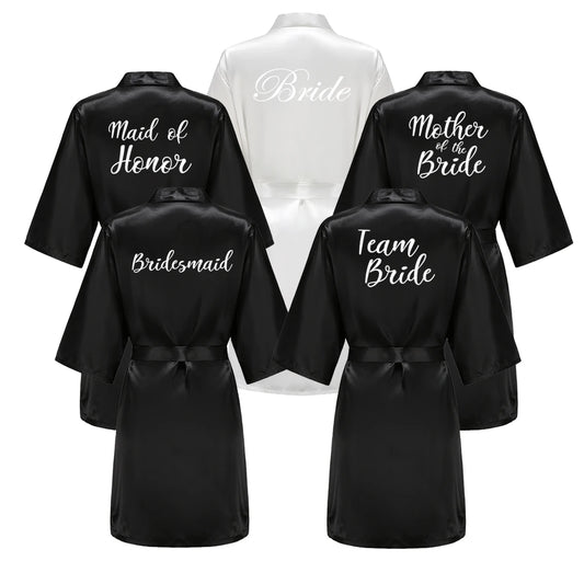 Black bridal party robes with bride, bridesmaid, mother of the bride, team bride and maid of honour text on the backs.
