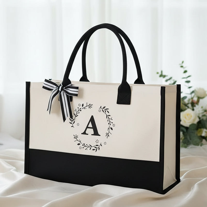 Black and white tote bag with floral design and letter 'A' on a white background