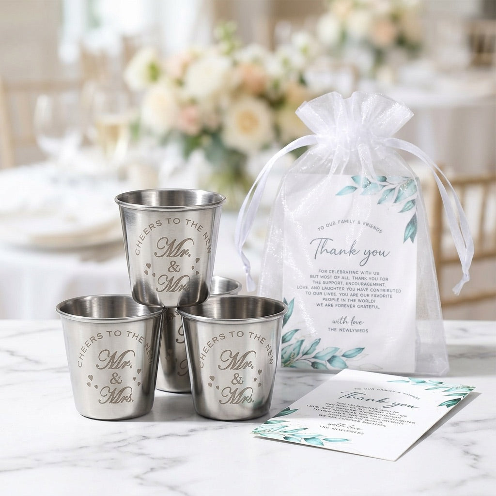 Set of silver cups with 'Mr. & Mrs.' engraving, a gift bag, and card on a marble surface.
