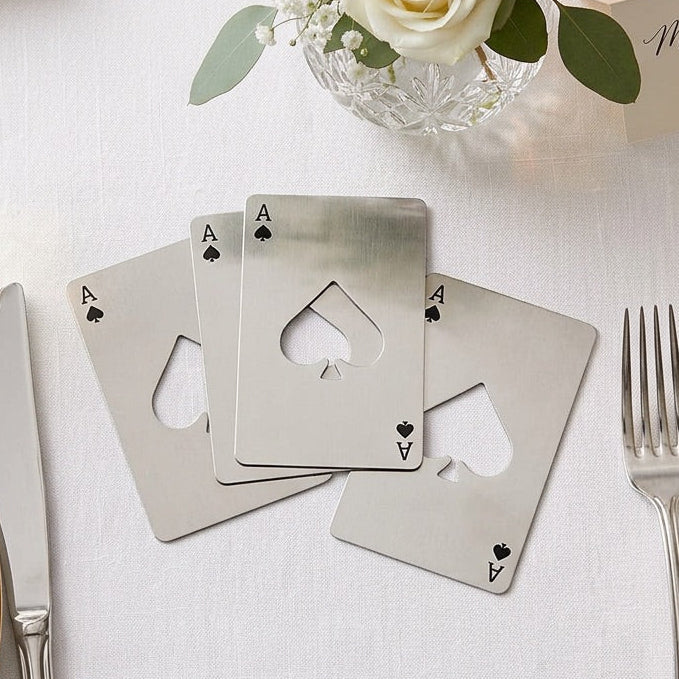 Silver playing card bottle opener favours on a table setting with flowers and name cards.