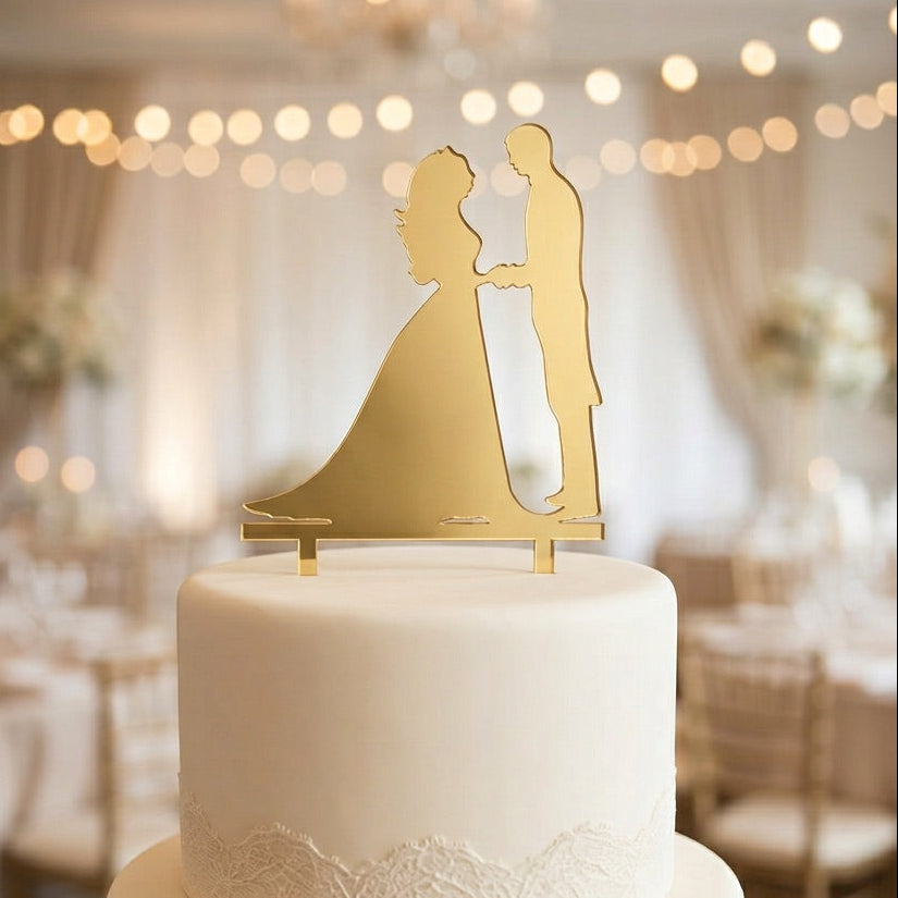 White wedding cake with gold silhouette topper in a decorated room