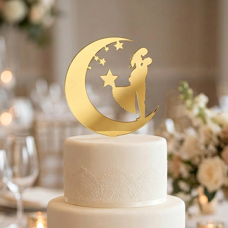 White wedding cake with a gold moon and star cake topper in a decorated setting.