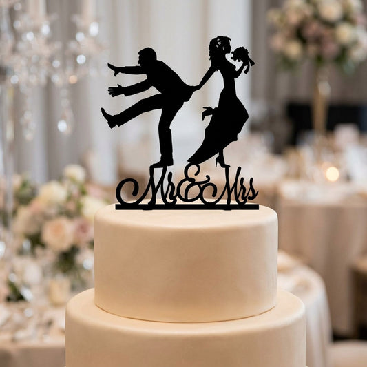 White wedding cake with a black 'Mr. & Mrs.' topper in a festive setting.