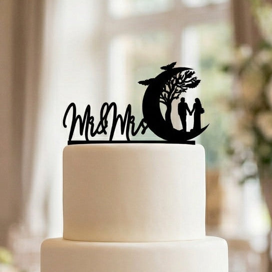 White wedding cake with 'Mr & Mrs' topper in a decorated room