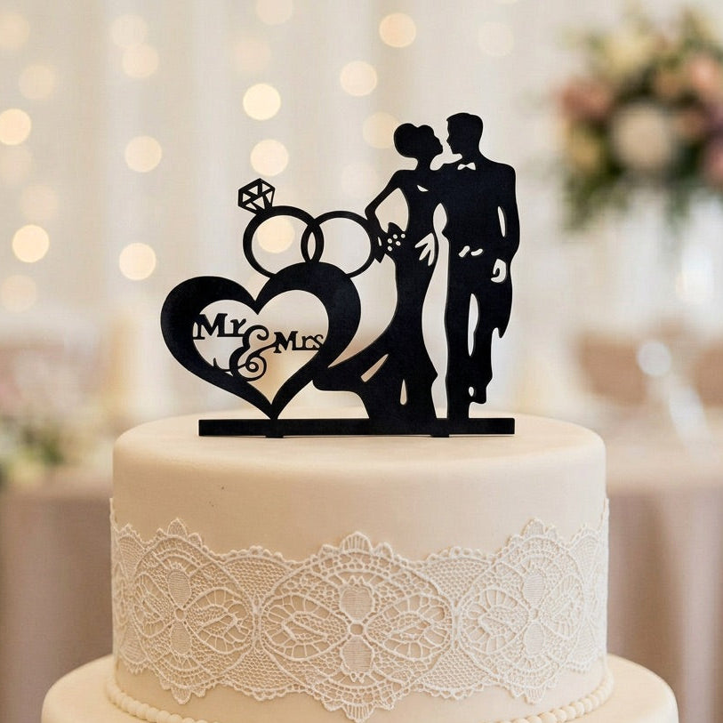 Wedding cake with a 'My Mrs' cake topper against a blurred wedding reception background.