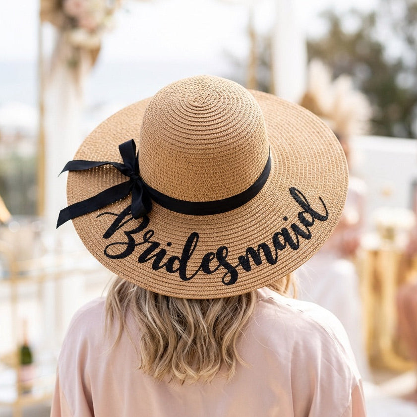 Person wearing a straw hat with 'Bridesmaid' text at an outdoor event.